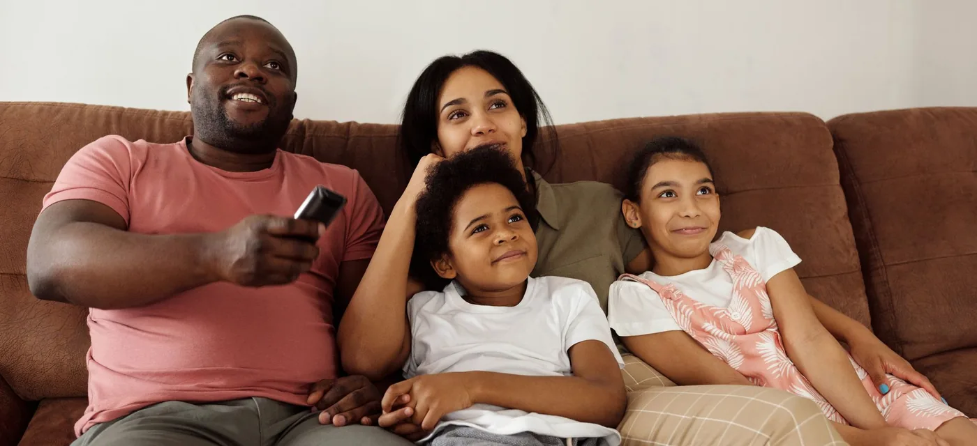 Família reunida no sofá assistindo TV durante o teste IPTV grátis